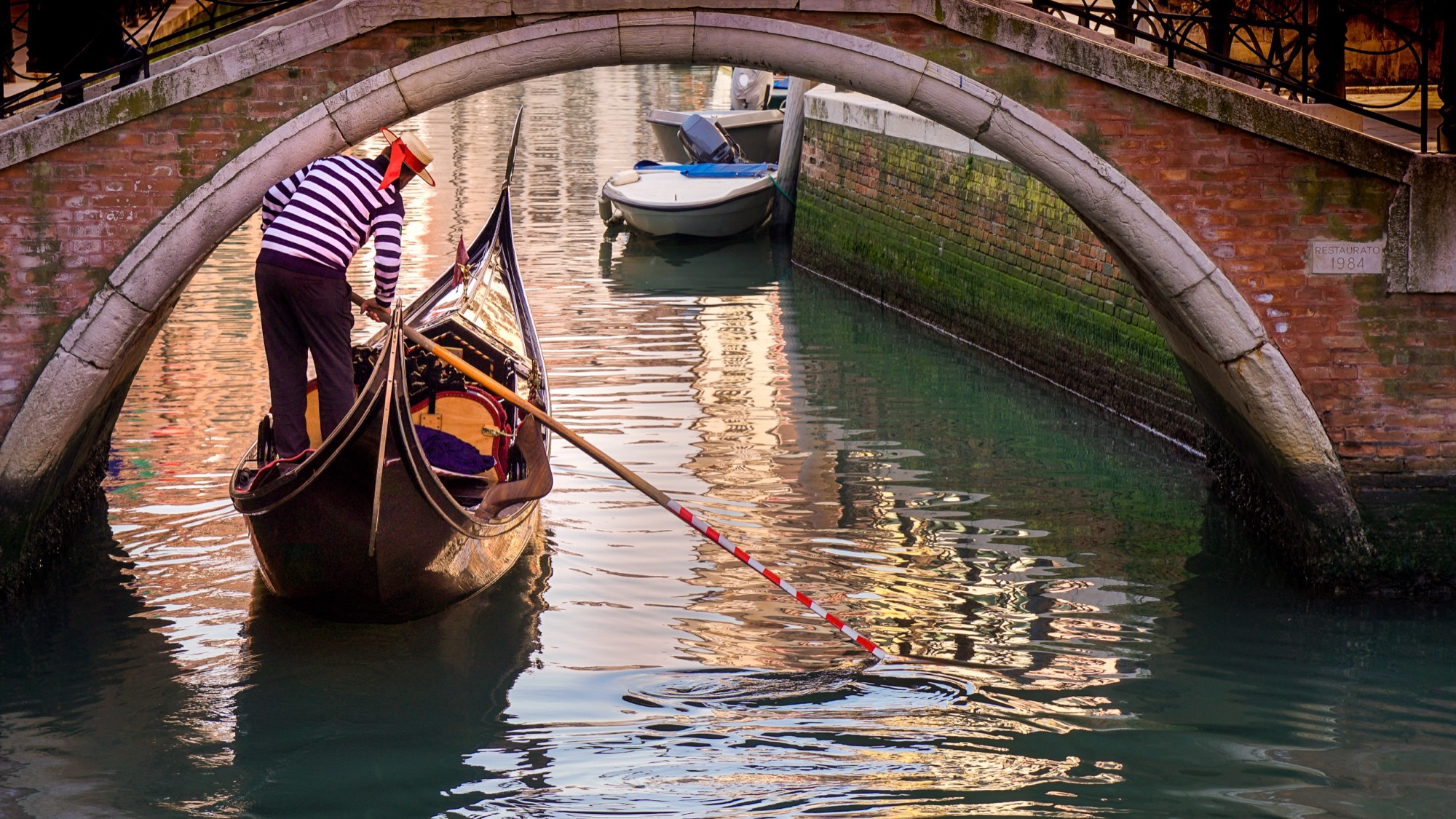 Gondola veneziana che passa sotto un ponte lungo un canale di Venezia